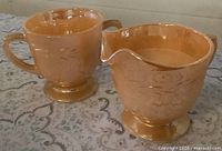 Front view of peach lustre Fire King Laurel creamer and sugar