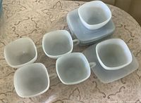 Six square teacups and six matching saucers displayed on table
