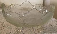 Side view of pressed glass footed bowl showing scalloped rim and floral pattern