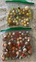 Two bags of assorted vintage glass marbles on patterned surface