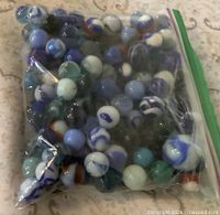 Full view of bag filled with assorted blue swirl glass marbles