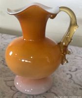 Front view showing butterscotch body, ruffled white-lined rim, clear amber handle, pink pedestal
