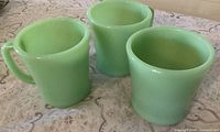 Three jadeite mugs upright showing colour and shape