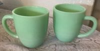 Two jadeite mugs upright showing color and shape