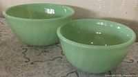 Two jadeite swirl bowls side by side