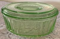 Side view of oval green uranium glass dish with lid fitted