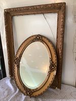 Oval mirror nested inside larger rectangular frame, showing scale and ornamentation