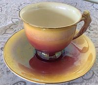 Teacup on saucer showing ombré glaze and gold rim