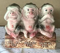 Front view of ceramic three-monkey coin bank showing see/hear/speak no evil pose, chest numbers and text on base