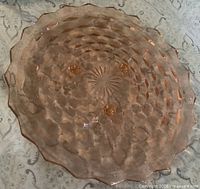 top view of pink depression glass cake plate showing cubist pattern and sawtooth edge