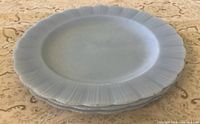 Stack of three light blue Pyrex plates, top view showing pie-crust rim
