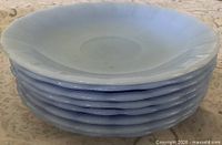 Stack of eight blue Pyrex saucers, side view