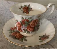 Teacup on saucer showing rose pattern and gold trim