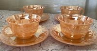 Front view of four peach lustre teacups on saucers