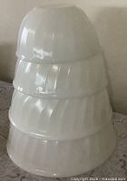 Four white swirl Fire-King bowls stacked, side view