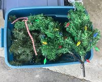 Bin containing multiple artificial evergreen mini trees with coloured LED light covers