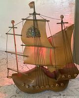 Front view showing wooden clog base, ship model, sails, rigging, red glow