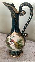 Full view of tall teal pitcher vase with handle and spout
