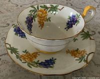 Teacup on saucer showing exterior floral design, gold trim and yellow foot