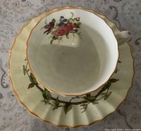 Overhead view of fluted teacup inside saucer showing yellow border and floral decoration