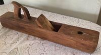 Side view of entire wooden hand plane showing handle, wedge, and body