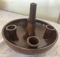 Oblique view showing brown glazed stoneware holder with central pillar and four side sockets