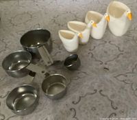 Stainless steel measuring cups and melamine duck cups displayed together