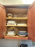 Overall view of dinnerware and bakeware inside cupboard