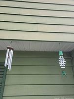 Two wind chimes hanging under eave
