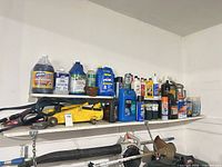 Shelves with assorted fluid containers, jack visible lower shelf