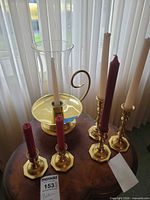 overview of brass candlestick holders, chamberstick with hurricane shade, and candles on table