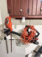 Hedge trimmer and leaf blower hanging, extension cord wrapped