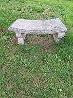 Front view of curved concrete garden bench on grass