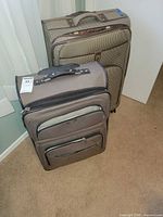 Front view of both Dockers rolling suitcases showing sizes, colors, exterior pockets and handles