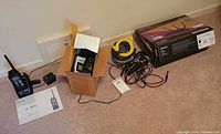 All items laid out: boxed Netgear router, Icom radio with adaptor and manual, SkyCaddie GPS in small box, yellow Ethernet and black audio cables visible