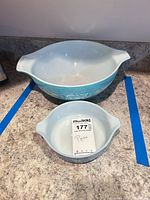 Two Pyrex Butterprint Cinderella bowls side by side showing size difference and interior wear