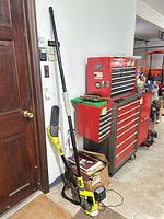 Full view of Ryobi telescoping pole saw standing beside toolbox