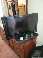 Full view of Sony TV on dresser with remotes and power cable