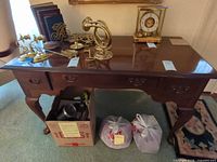 Front view of mahogany finish console table with three drawers and cabriole legs