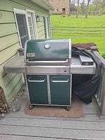 Front view of Weber Genesis propane grill with cabinet base and side shelf