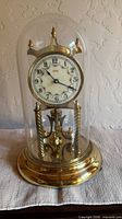 Front view of brass anniversary clock under glass dome