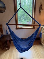 Front view of blue yarn hammock chair hanging from ceiling showing full seat and wooden spreader bar