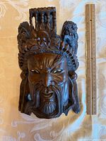 Front view of entire carved wood mask beside 12-in. ruler