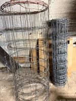Both rolls of galvanized wire fencing standing upright