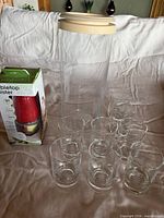 Overall lot showing tabletop mister in box, tall glass canister, eight juice glasses