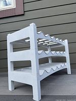 assembled three-tier white plastic wine rack viewed from side