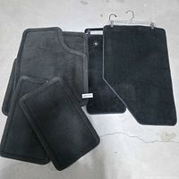 five carpeted car mats laid out showing colors and shapes