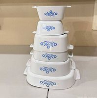 Stacked view of all six CorningWare dishes showing graduated sizes and cornflower pattern