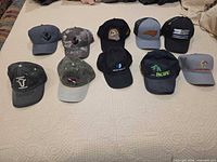 All 11 caps laid out on bed showing variety of styles and colors