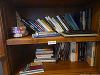 Full view of bookshelf showing DVD spindle, two shelves of books and picture frames